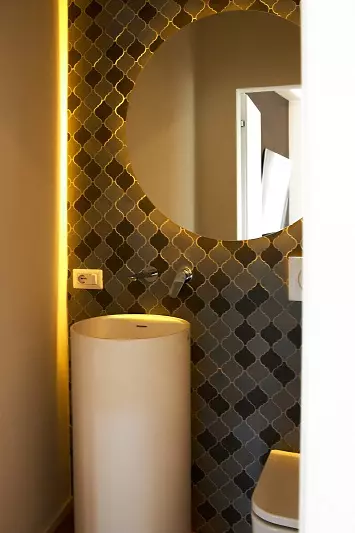 Un piccolo bagno ospiti di design con lavabo freestanding e rivestimento a parete in mattonelle arabe. Il lavabo freestanding è posizionato al centro della stanza, creando un punto focale elegante. Le mattonelle arabe creano un'atmosfera esotica e vibrante. Il design del bagno è curato nei minimi dettagli, con una combinazione di colori e materiali raffinata.