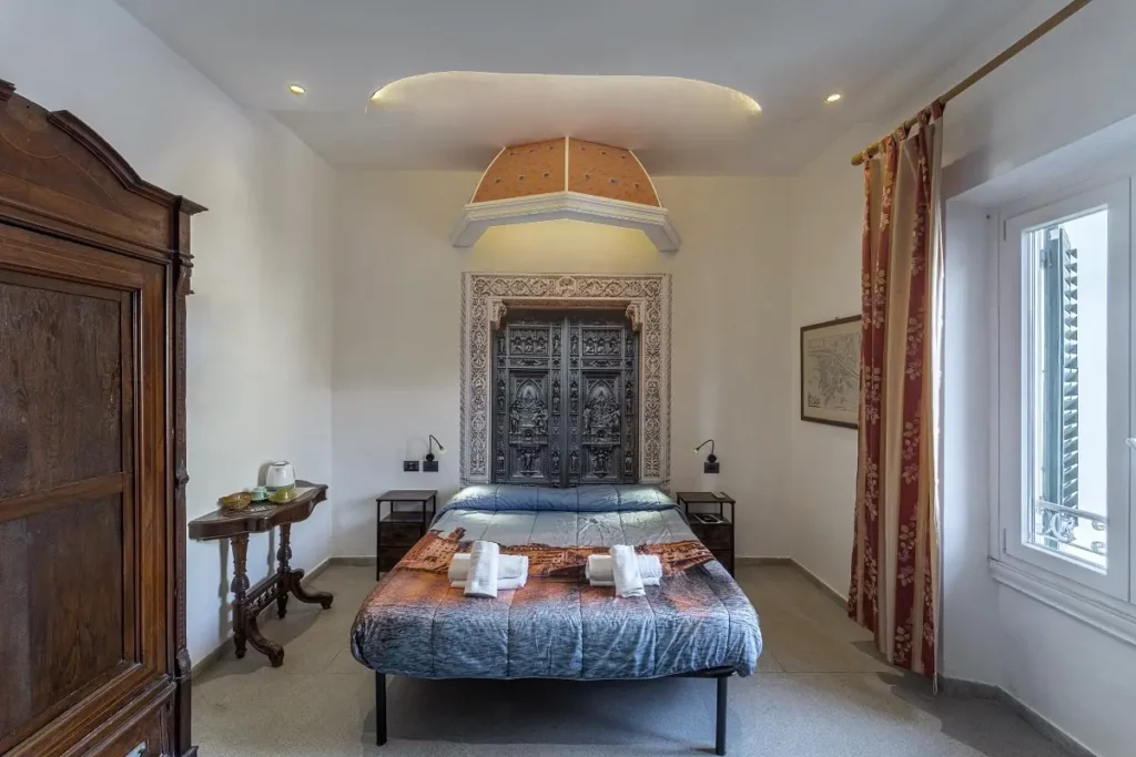 Camera da letto matrimoniale in un B&B di charme a Firenze, dedicata a Filippo Brunelleschi. Cupola artigianale, porta in legno intagliato e arredi in stile rinascimentale. Ideale per coppie in cerca di un'esperienza autentica. Ristrutturazione B&B, progettazione di interni, design d'interni Firenze.