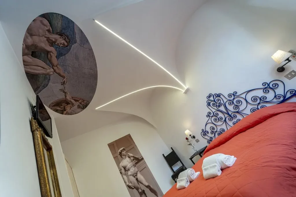 Stanza di un B&B a tema Michelangelo, progettata con un design raffinato e ispirato all'arte rinascimentale. L'ambiente unisce eleganza e comfort, con dettagli artistici che richiamano le opere del celebre pittore e scultore. Un esempio perfetto di studio progettazione hotel, dove ogni elemento è pensato per offrire un'esperienza unica e immersiva.